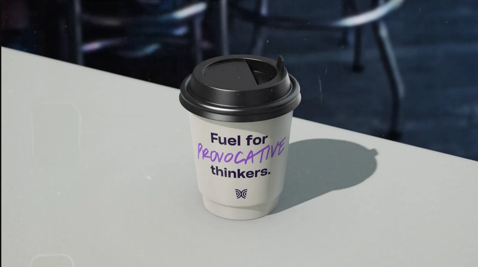 A MITRA coffee cup on a table, printed with “Fuel for provocative thinkers.”